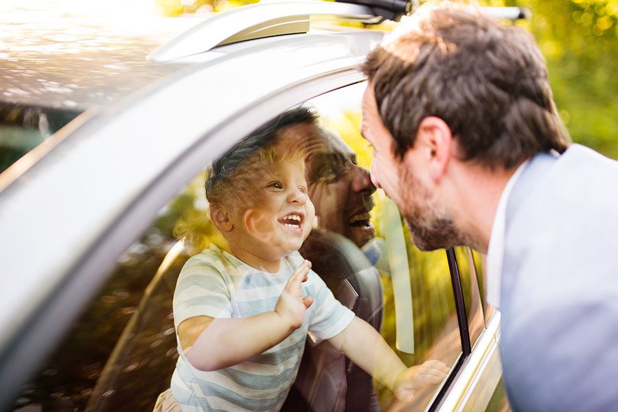 Insurance Quote - Father Making Silly Faces Through the Car Window at His Excited Son